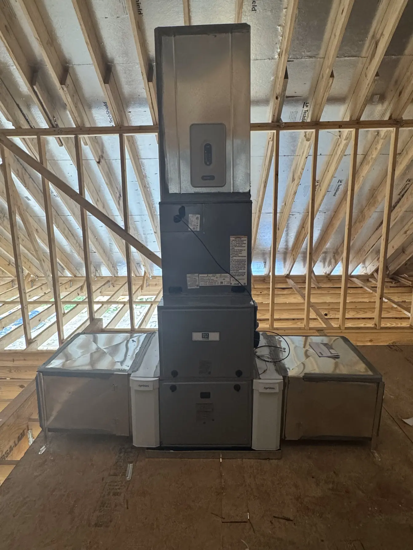 New furnace and air-handler stack with twin AprilAire filter cabinets in a new-construction attic