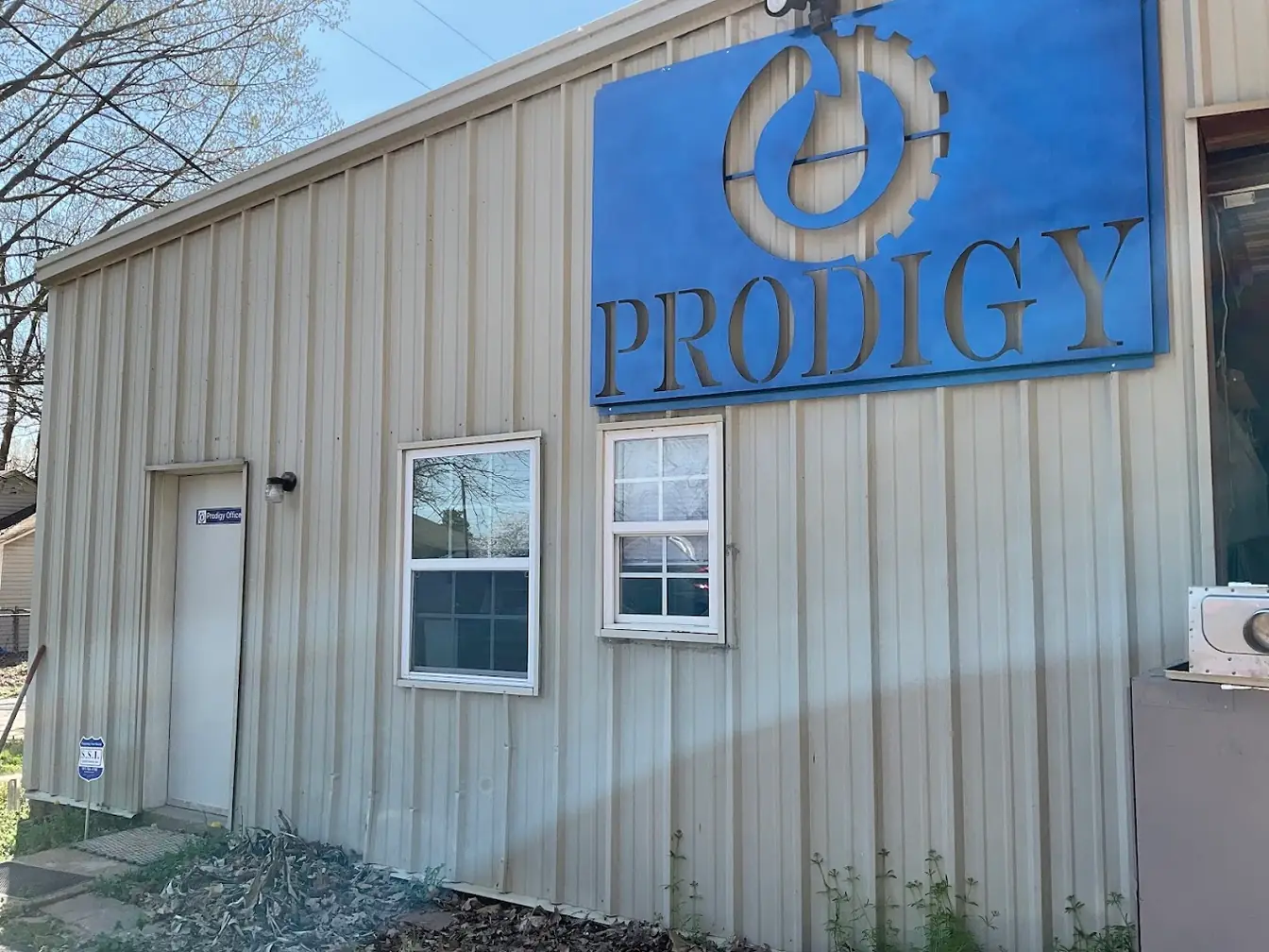 The Prodigy shop — a metal building with the blue Prodigy gear-and-drop sign