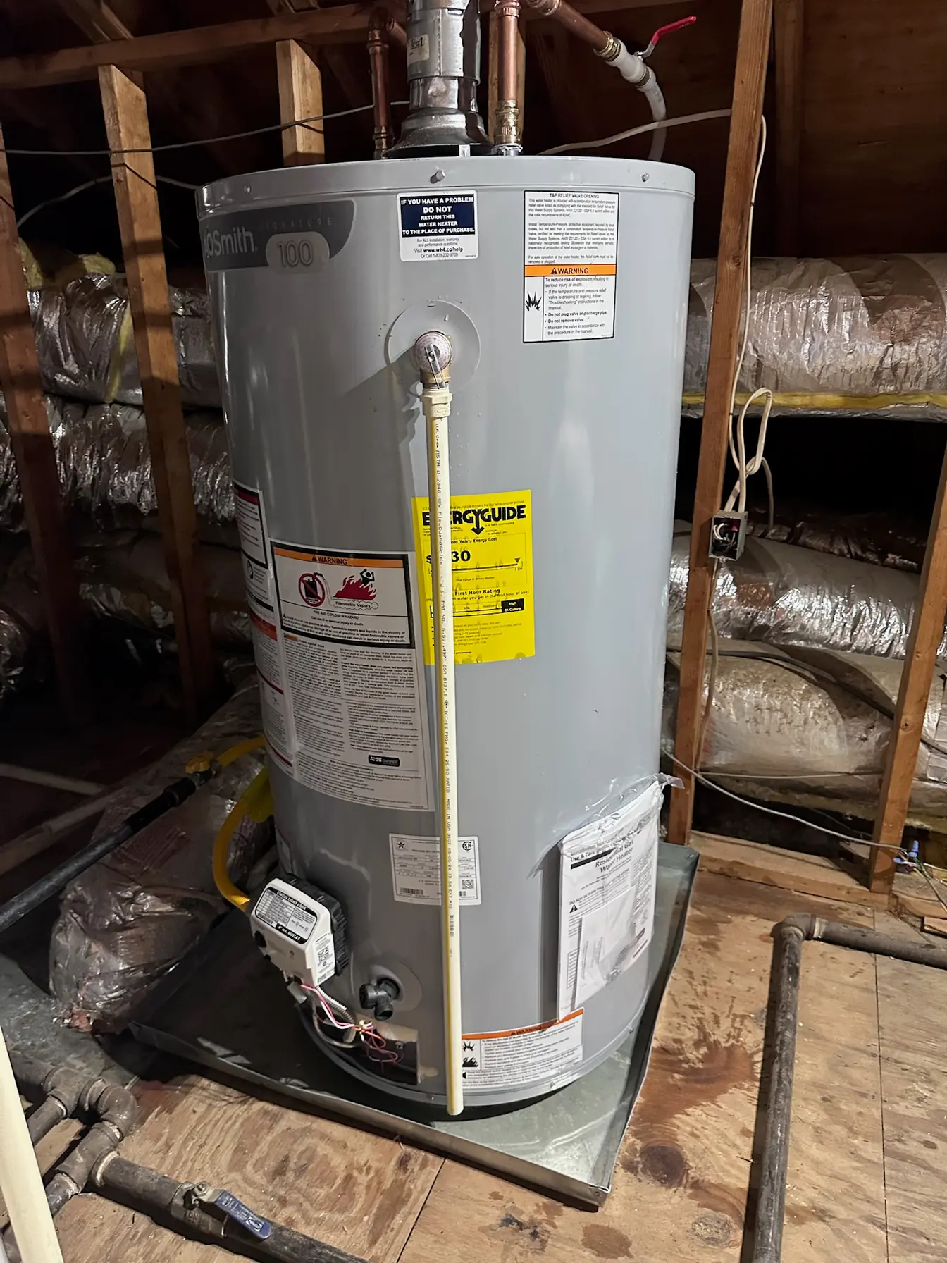 New A.O. Smith tank water heater installed in an attic, set in a drain pan with the T&P discharge line run